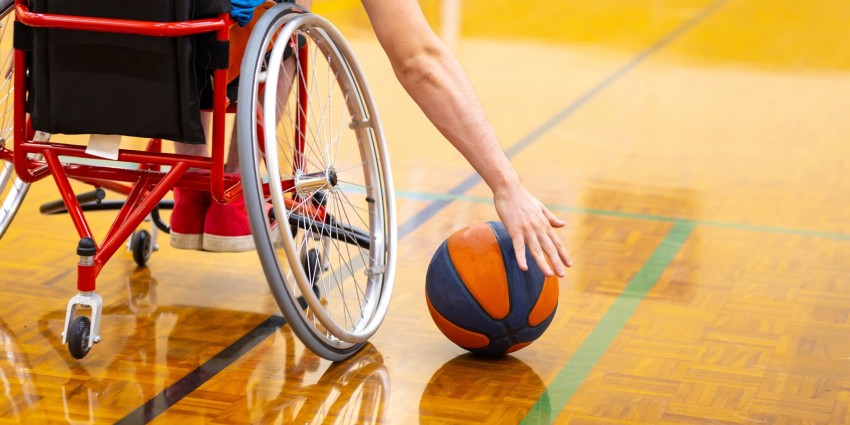 Image of basketball player in wheelchair reaching out to pick up basketball