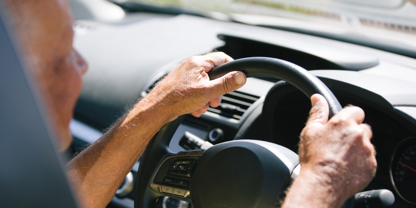 a driver with with their hands on the steering wheel of a car