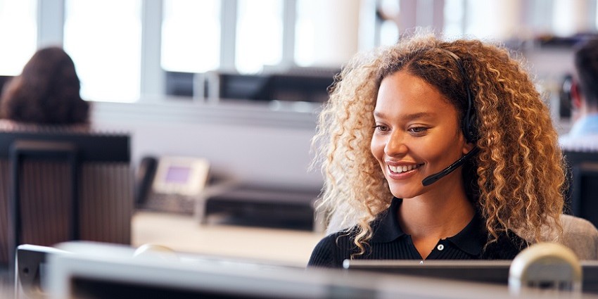 A woman smiling while taking a call in a call centre