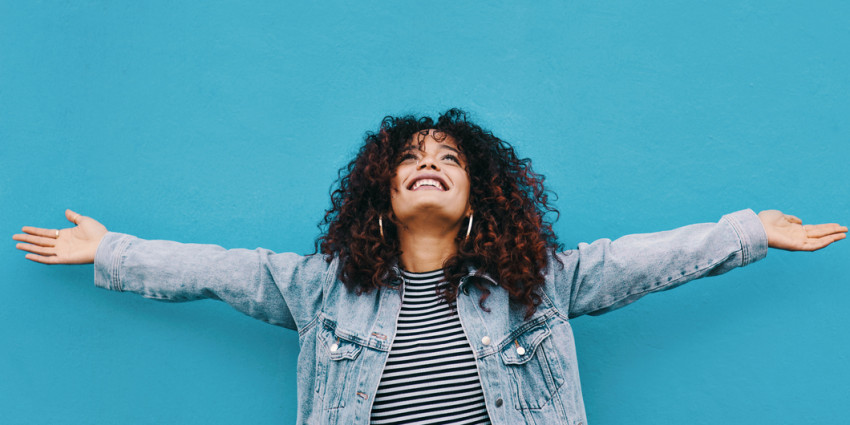 young woman standing with her arms outstretched against a blue background