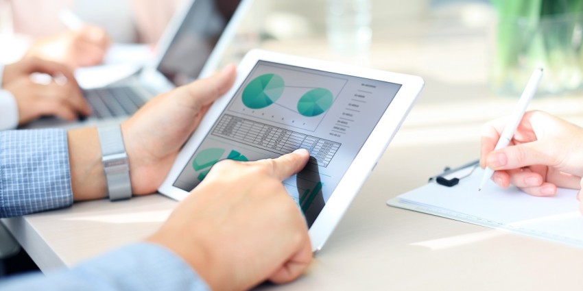 Image of two people working on a laptop and tablet, showing hands only
