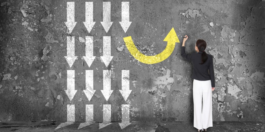 Women drawing a concept intiative on a wall, will small arrows going down and her big arrow going up