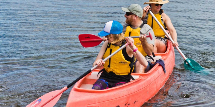 Family kayaking at Camp Quaranuo in a 3 person kayak