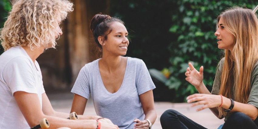 photo of three young people outdoors chatting