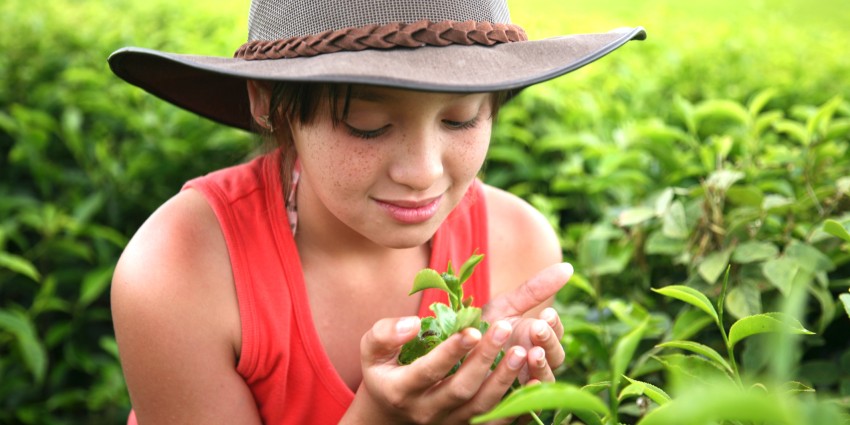 Image of a young teenage girl wearing an wide-rimmed hat and surrounded by nature