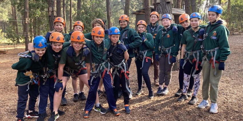 Image of a group of young kids in a group photo - dressed in cadet gear with safety helmets - ready to go climbing