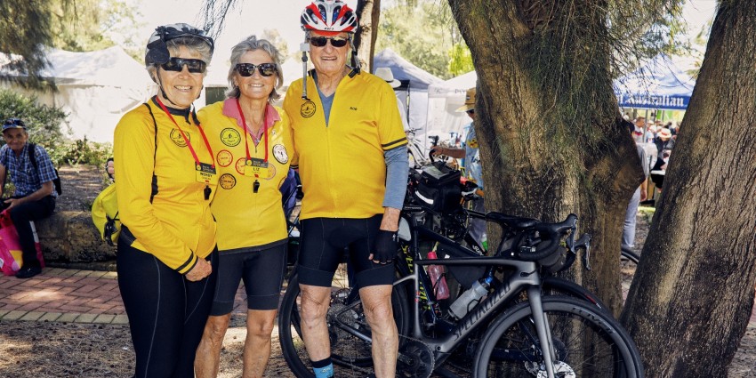 photo of three over 55 seniors in biking clothes, helmets and with their bikes