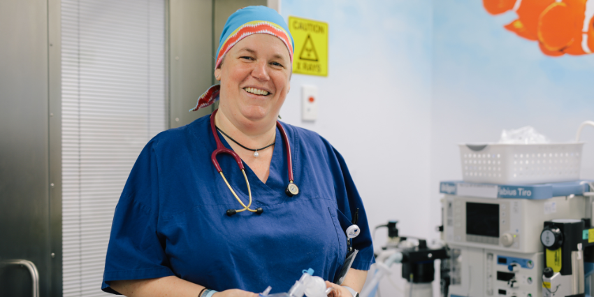 Professor Britta Regli-von Ungern-Sternberg wearing scrubs and a stethoscope is standing in a hospital.