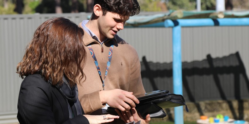photo of two professional workers working with an ipad and phone at a child care centre