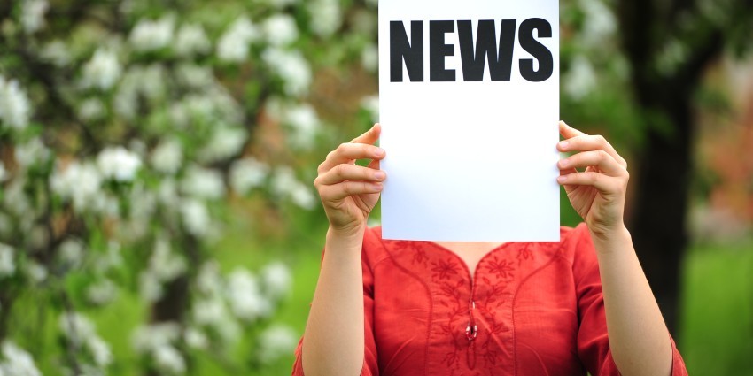 image of a woman holding a sign up that reads "News"
