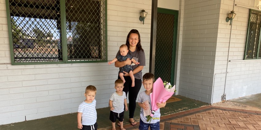 image of a mother with her 3 children out front of their house