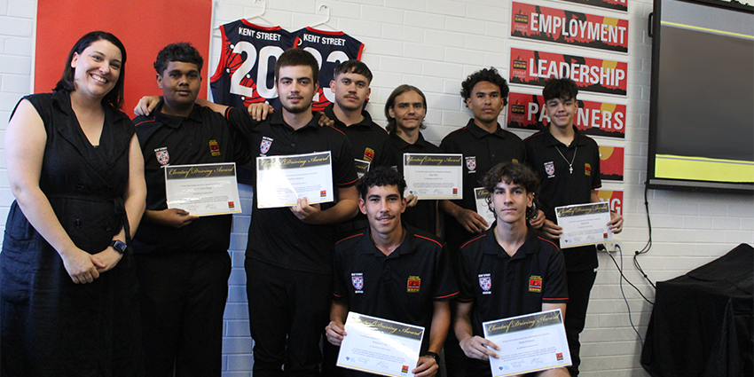 a group of people standing against a wall holding certificates