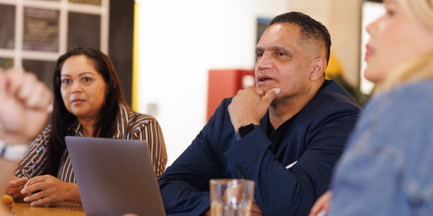 Aboriginal Australian man at meeting with Indigenous colleagues in creative modern workspace.
