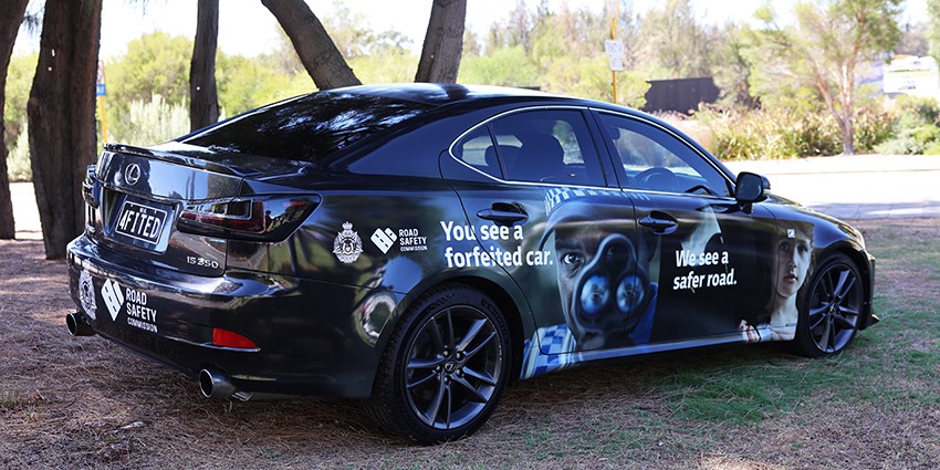a black car covered with road safety messaging parked next to a tree