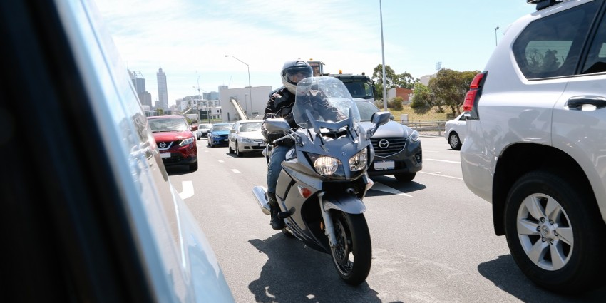 a motorcycle lane filtering between two cars