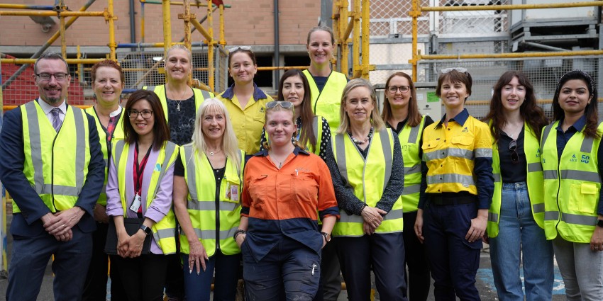 A group of women and one man in hi-vis vests on a construction site