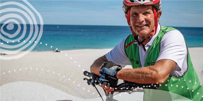 Photo of an elderly man on a push bike with the beach in the background