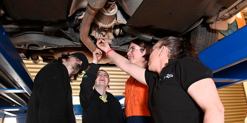 Three TAFE college automotive students, inspecting a car with their lecturer.
