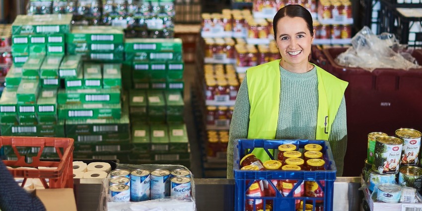 Photo of a young female Food Bank worker in a warehouse filled with food