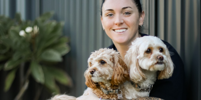 a young adult woman smiling and hugging two pet dogs