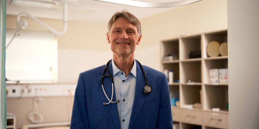 Headshot of Markus Scheliach in a medical room. Wearing a blue blazer with a stethoscope slung around his neck.