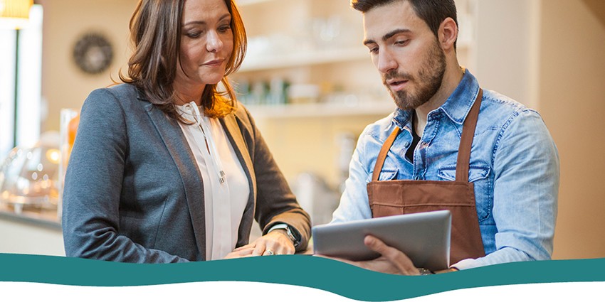 A cafe owner showing a professional businesswoman information on a tablet