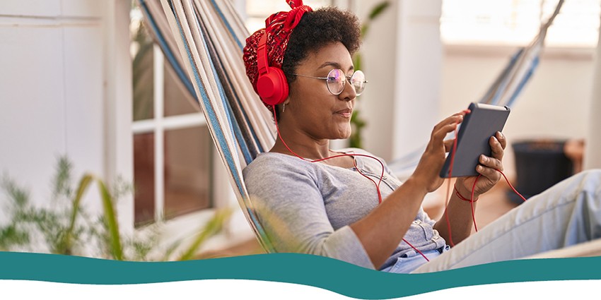 A lady sitting in a hammock watching a video on a tablet