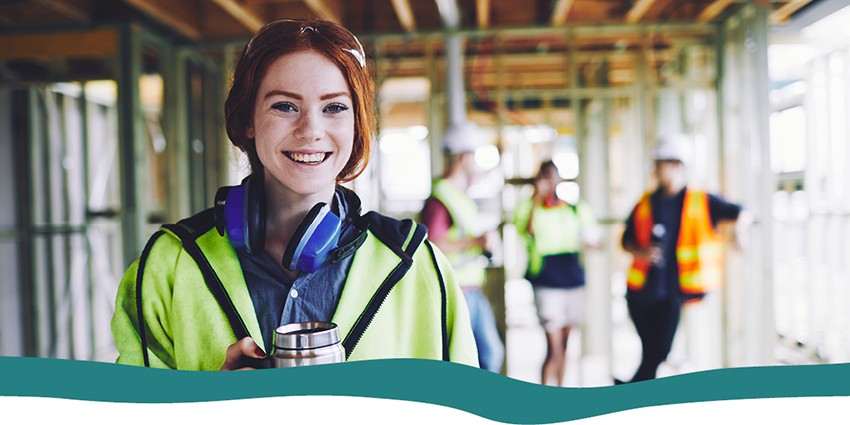 A construction worker in hi-vis vest holding a cup of coffee on construction site