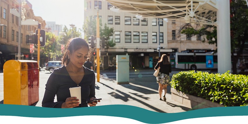 A woman walking around Perth city looking down at her phone