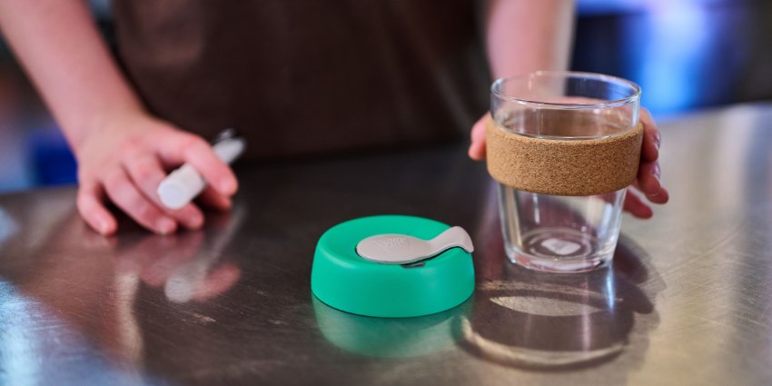 a barista with a reusable cup and lid