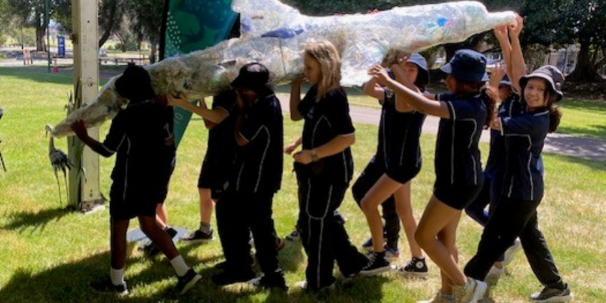 Primary school students carrying a scrap dolphin filled with rubbish collected during River Rescue Day.