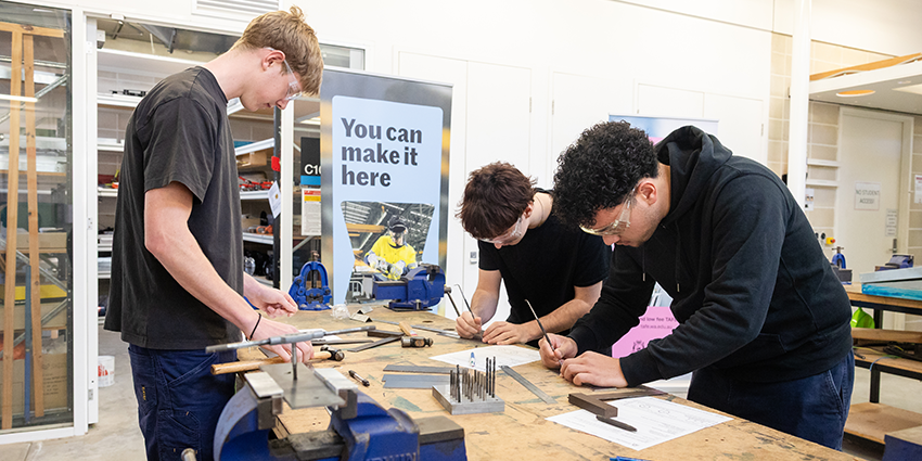 three male students working at a workshop setting