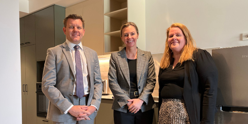 Three departmental representatives inside a Common Ground apartment, smiling