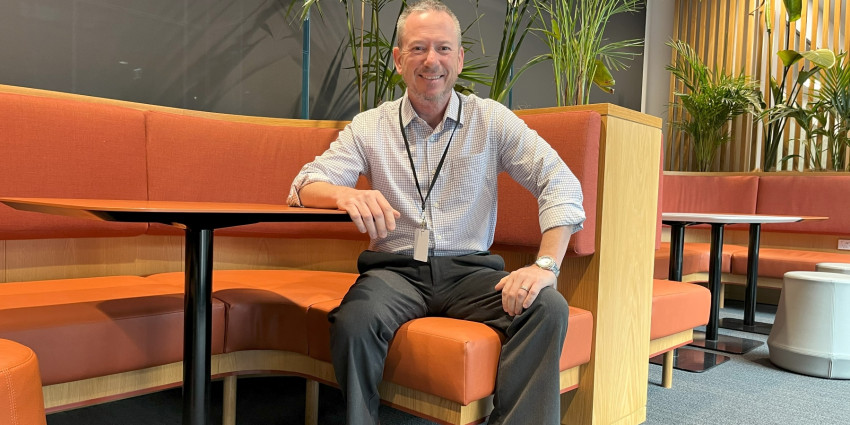 a man dressed in neat casual clothing sitting in a work office environment