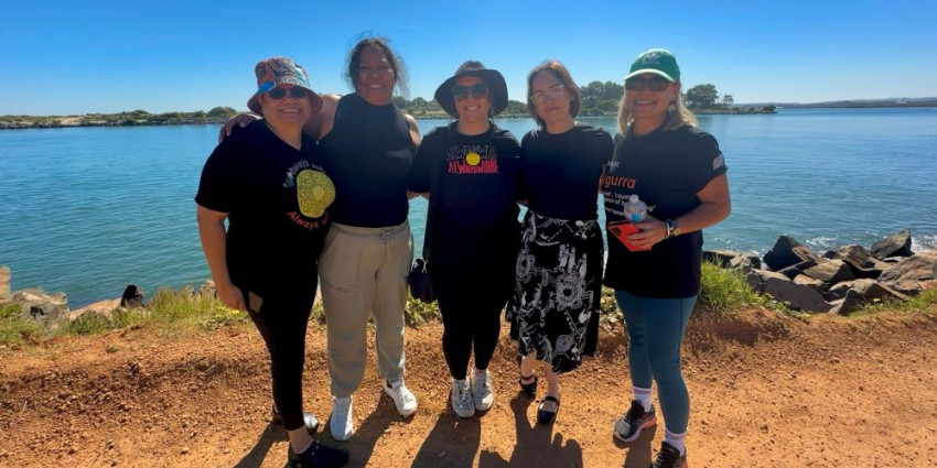 5 women standing in front of a body of water