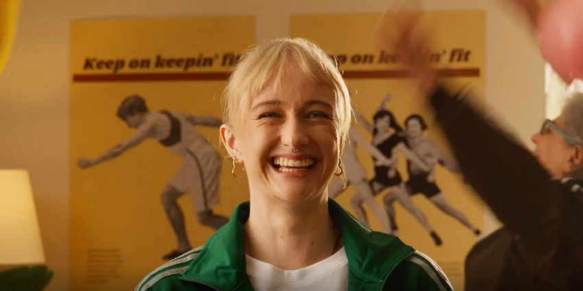 female facing the camera smiling with female in the background and posters on the wall