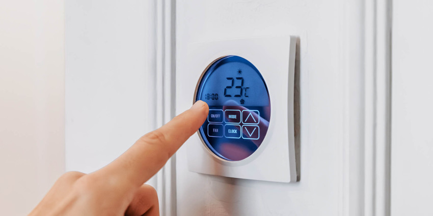 Person's hand touching a household temperature control panel