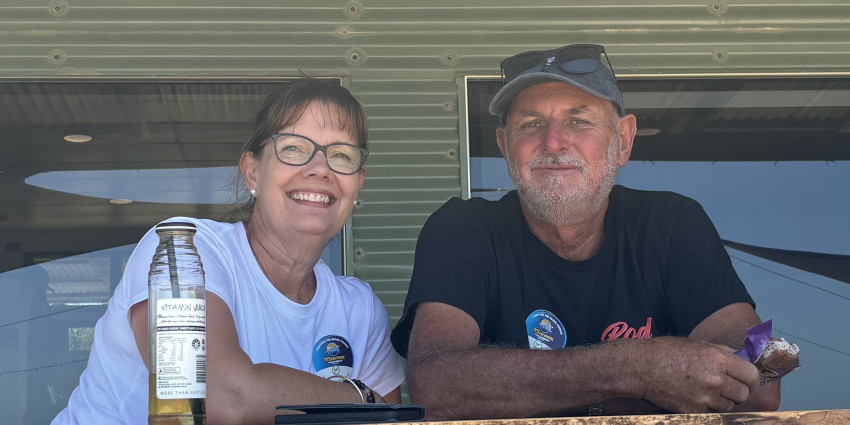 A man and woman sitting on a front verandah, smiling