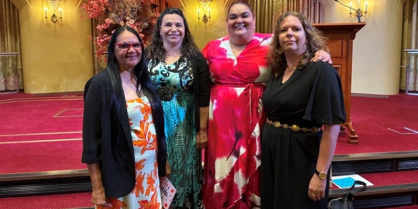 Four Aboriginal women, smiling, well dressed, in an indoor setting
