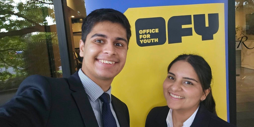 Two members of the Ministerial Youth Advisory Council taking a selfie in front of the Office for Youth pull-up banner.