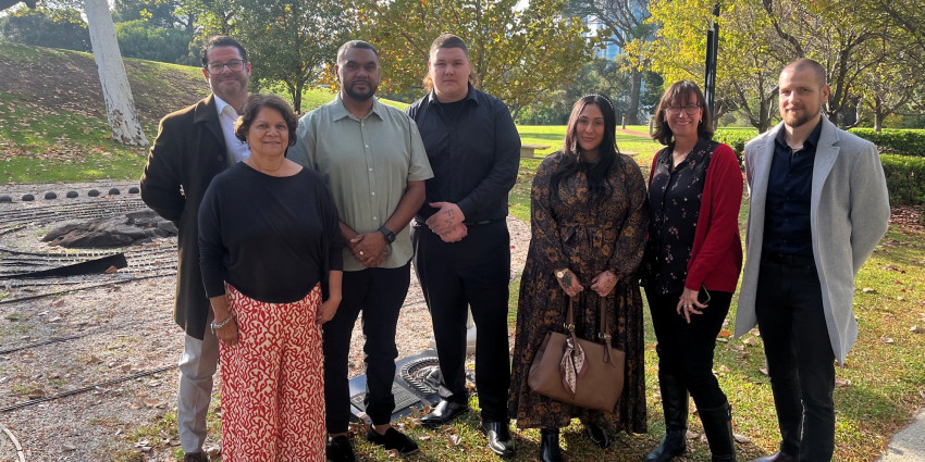 Group shot of seven neatly dressed adults in an outdoor setting