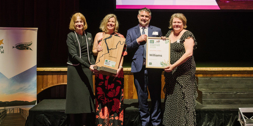 Four people holding an award and certificate on a stage at an awards event.