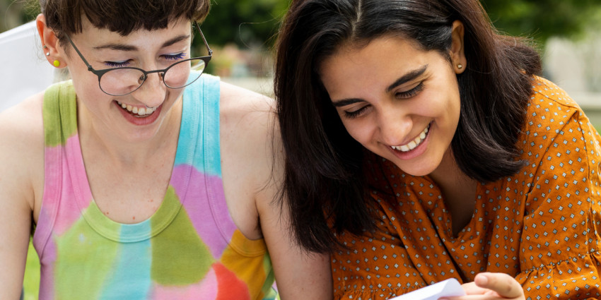 Two students looking at papers and sharing a laugh