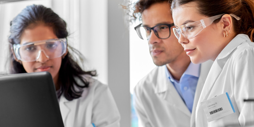 Three students in science laboratory looking at computer
