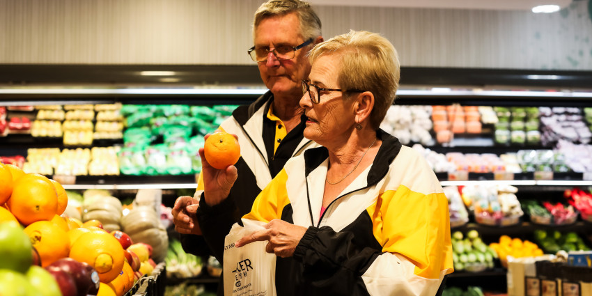 A middle aged couple shopping for fruit and vegetables in a grocery store