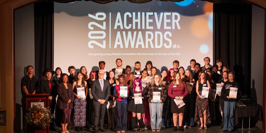a large group of young people on stage holding their Achiever Awards with "2026 Achiever Awards" signage in the background