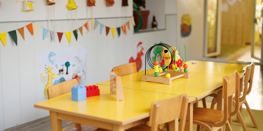 A timber table and chairs in an empty early learning centre room with learning toys on the table