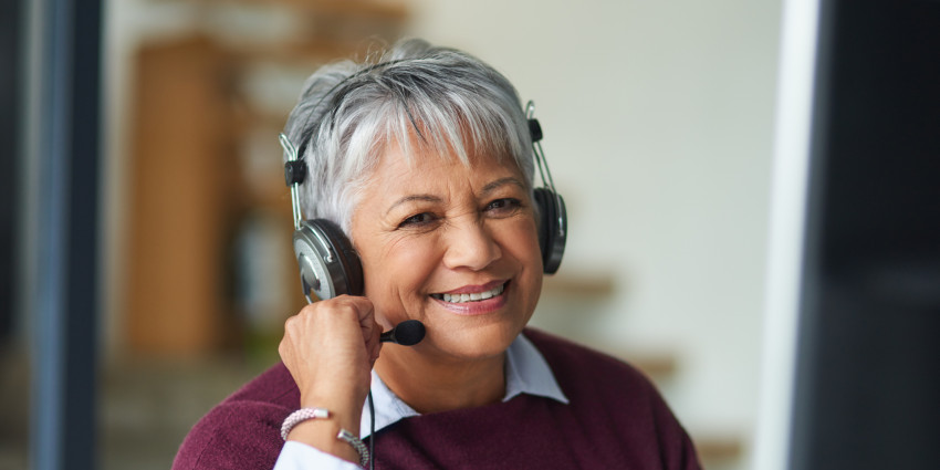 a woman smiling, talking on the phone using a headset