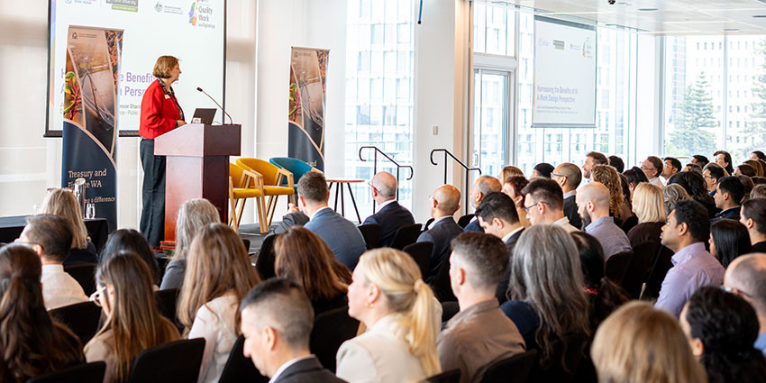 Professor Sharon Parker speaking in front of a big crowd at the Public Sector Economic Forum 2026