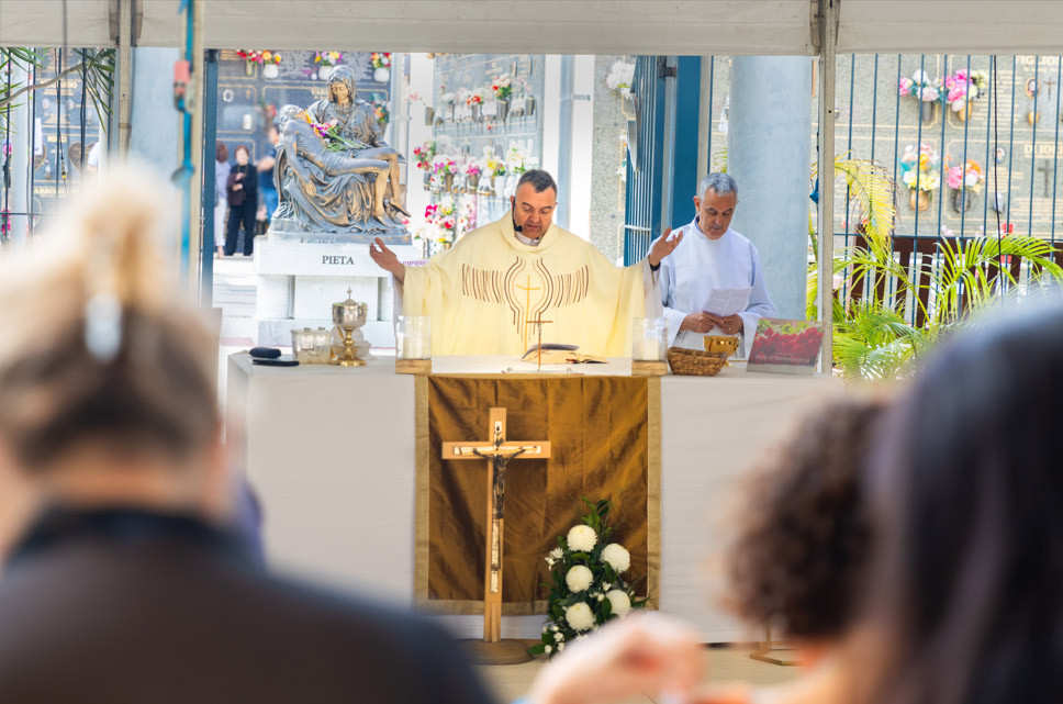 Father conducting mass at altar with arms outstretched